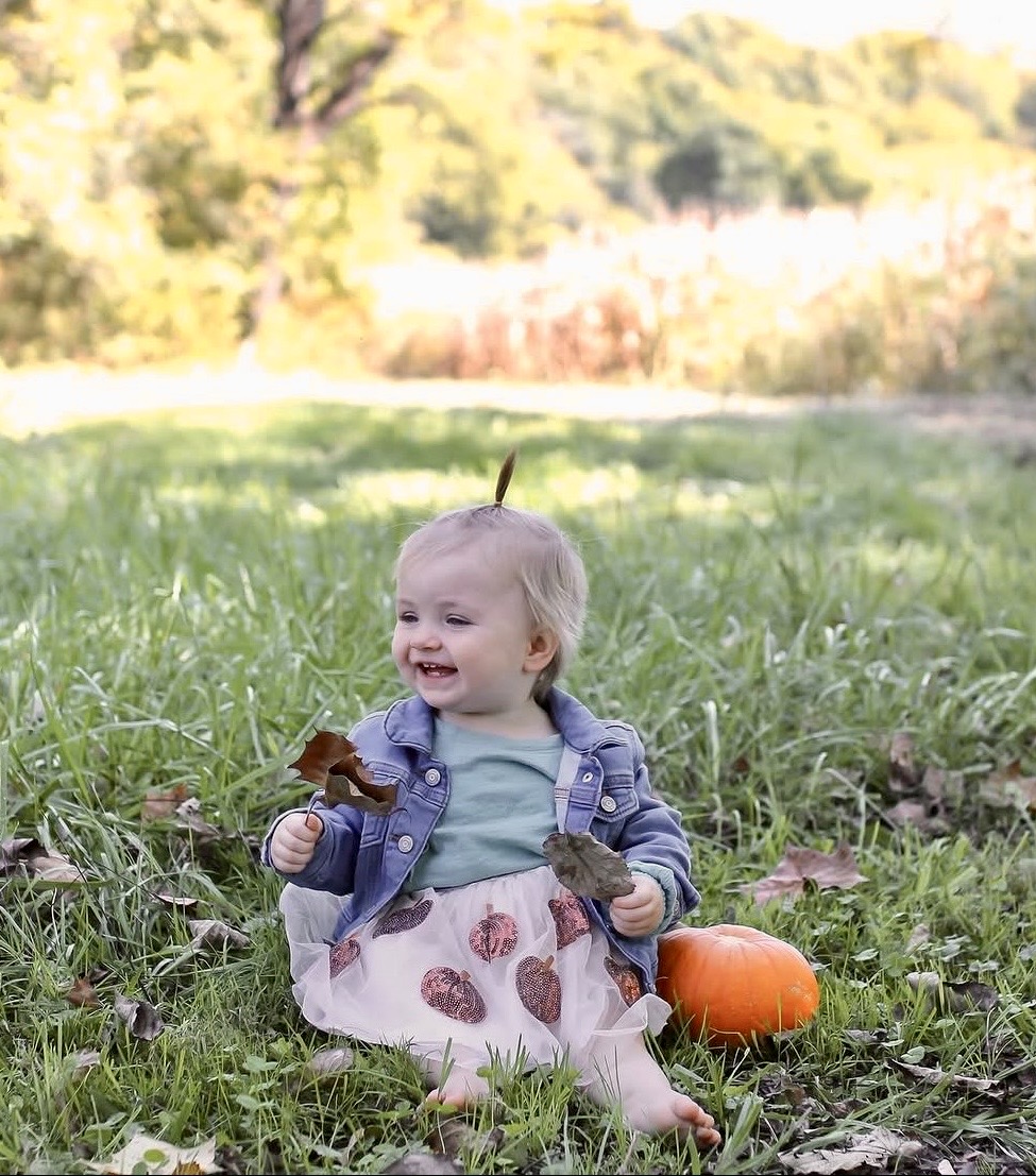 Baby seated outdoors in an autumn portrait